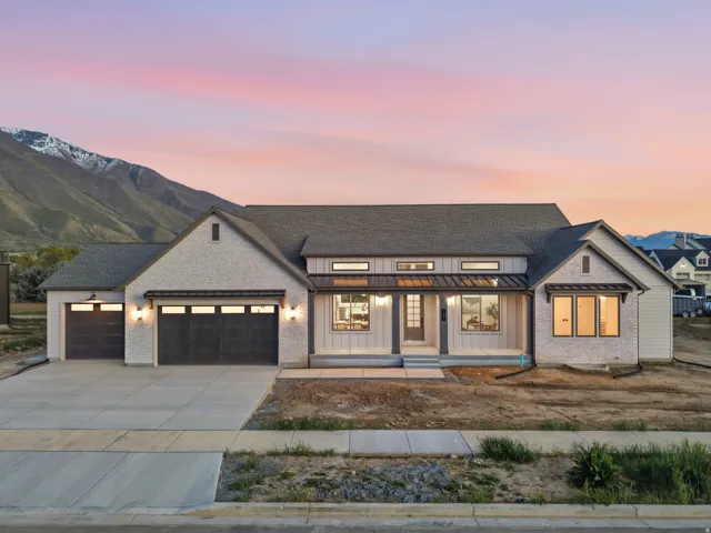 Modern inspired farmhouse with covered porch, a standing seam roof, a garage, concrete driveway, and board and batten siding
