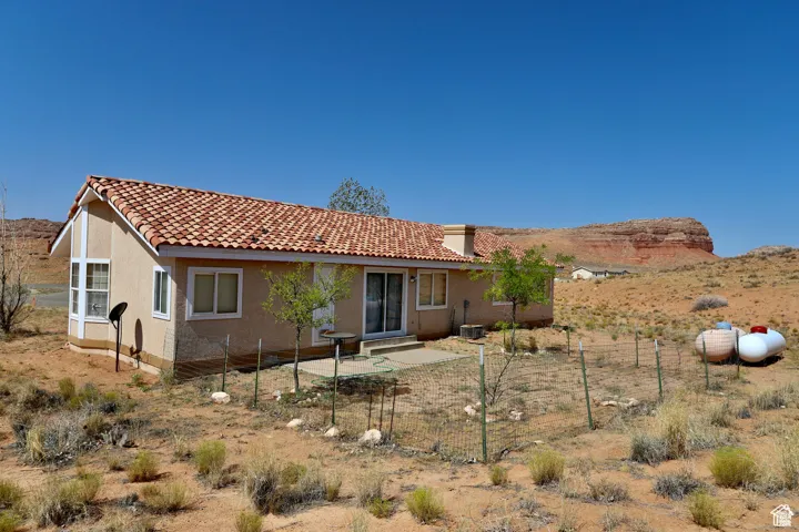 Rear view of house with a tile roof, stucco siding, and a patio area