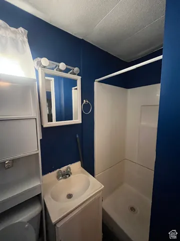Full bathroom featuring a shower stall, a textured ceiling, and vanity