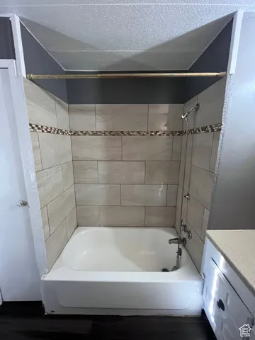 Bathroom featuring tub / shower combination, vanity, dark wood-style flooring, and a textured ceiling