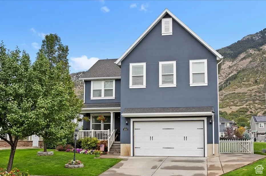 Traditional-style home with covered porch, stucco siding, an attached garage, driveway, and roof with shingles