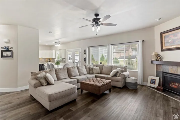 Living area featuring healthy amount of natural light, dark wood finished floors, a tile fireplace, and ceiling fan