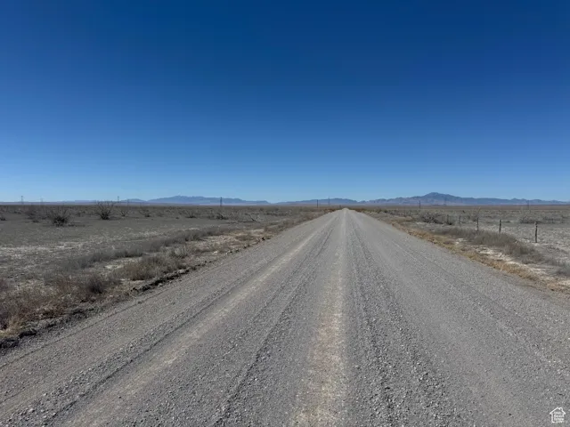 View of dirt / gravel road featuring a view of countryside and a mountain view