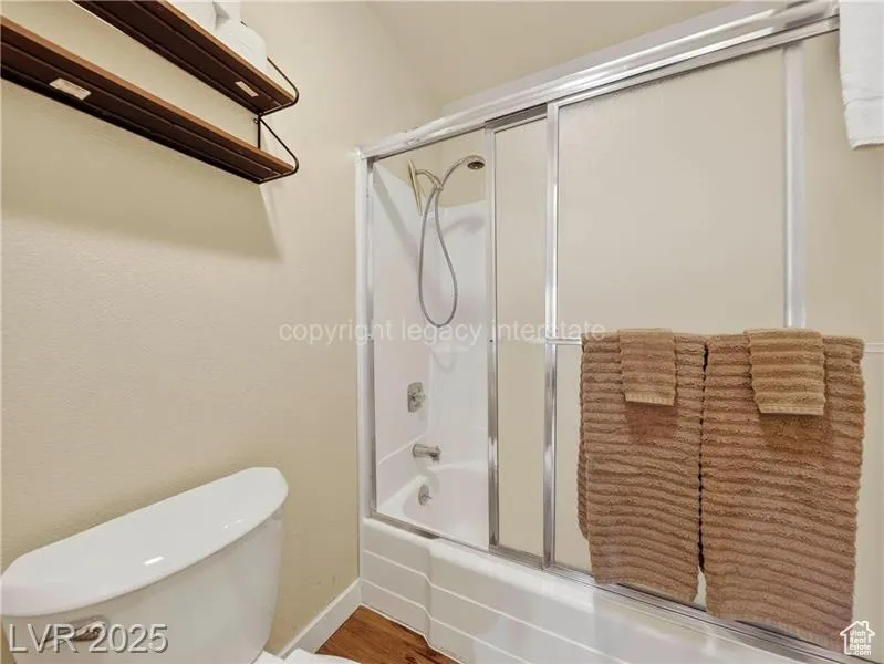 Bathroom with shower / bath combination with glass door and wood finished floors