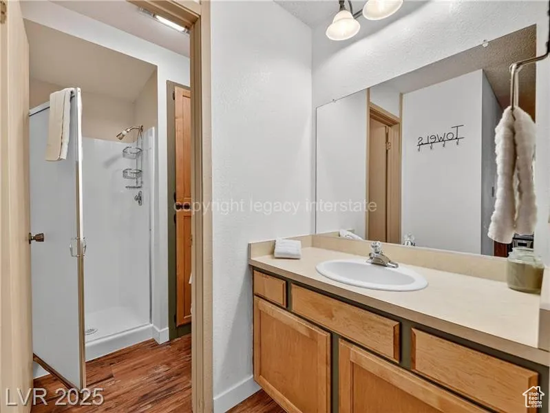 Full bathroom featuring a stall shower, vanity, and dark wood-style flooring