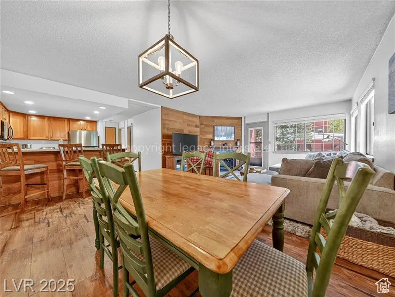 Dining area with wood walls, wood finished floors, a textured ceiling, and a chandelier