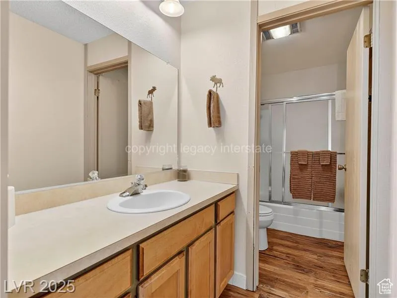 Bathroom featuring bath / shower combo with glass door, vanity, and light wood-type flooring