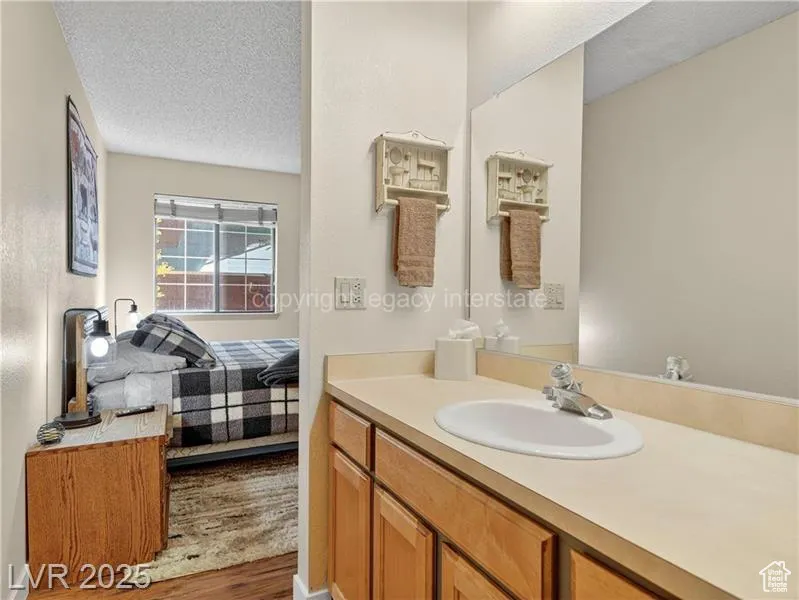 Ensuite bathroom featuring a textured ceiling, vanity, and wood finished floors
