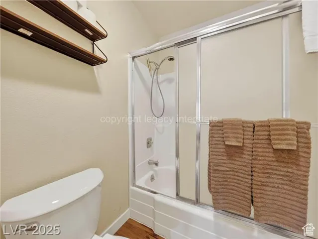 Bathroom with shower / bath combination with glass door and wood finished floors
