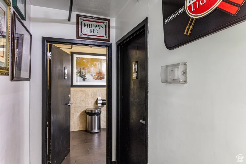 Hall with dark wood-type flooring and tile walls