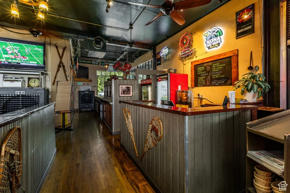 Kitchen featuring dark countertops, dark wood-style flooring, a ceiling fan, and a peninsula