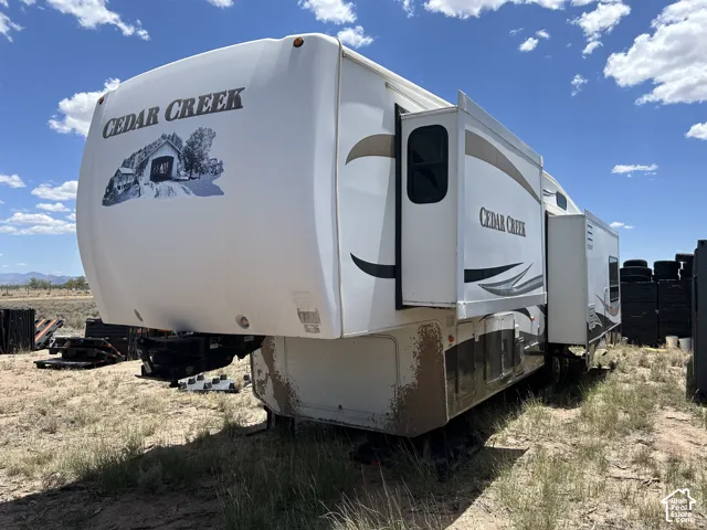 White fifth-wheel RV featuring Cedar Creek branding and multiple slide-out sections