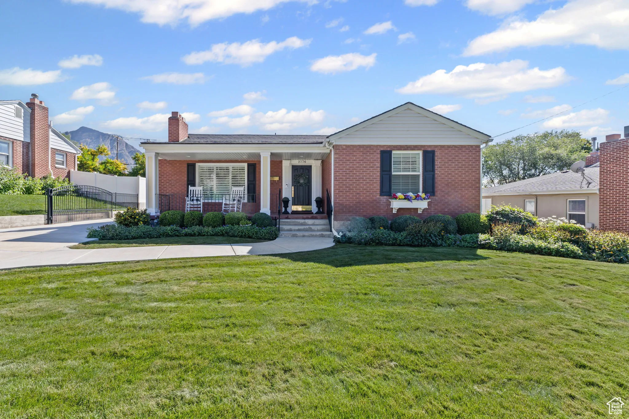 View of front of house with covered porch, brick siding, and a chimney