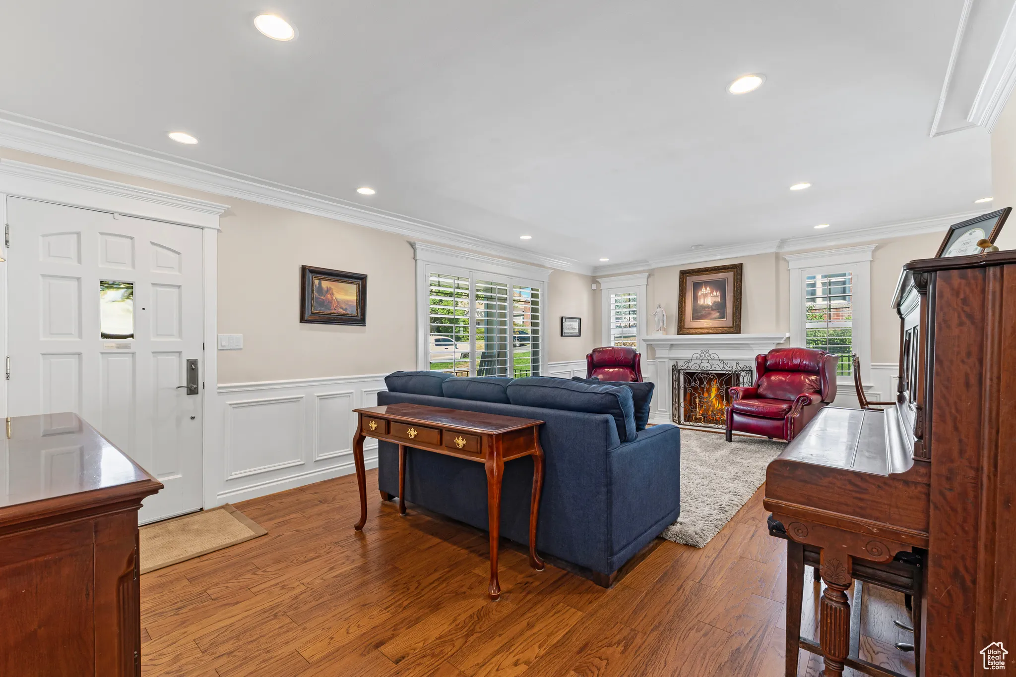 Living room featuring plenty of natural light, wood finished floors, ornamental molding, recessed lighting, and a decorative wall