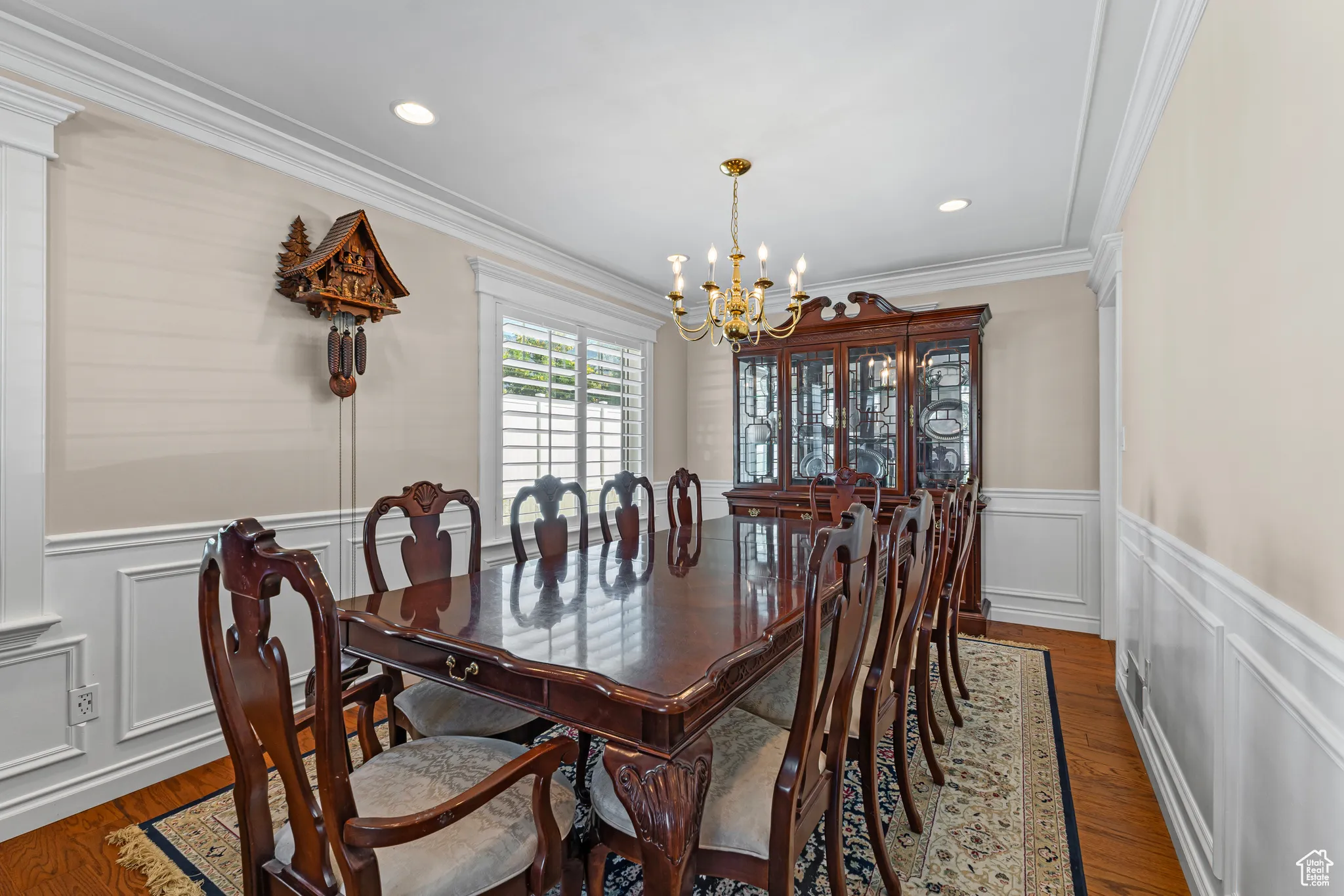 Dining space with a decorative wall, a wainscoted wall, ornamental molding, wood finished floors, and a chandelier
