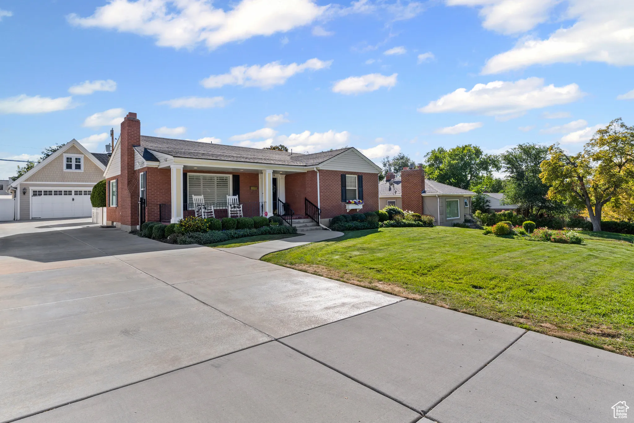 View of front facade with covered porch, a garage, a front lawn, concrete driveway, and brick siding