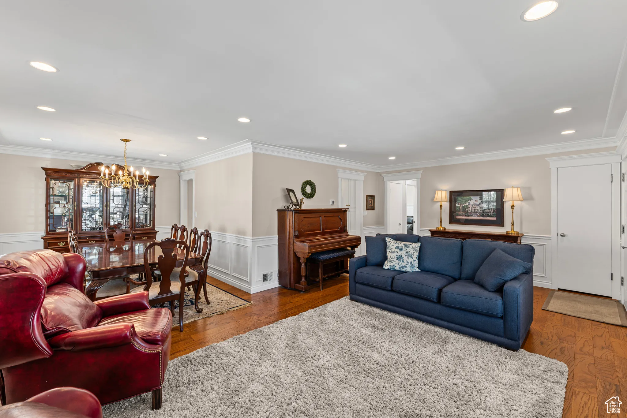 Living room with wainscoting, a decorative wall, wood finished floors, recessed lighting, and a chandelier