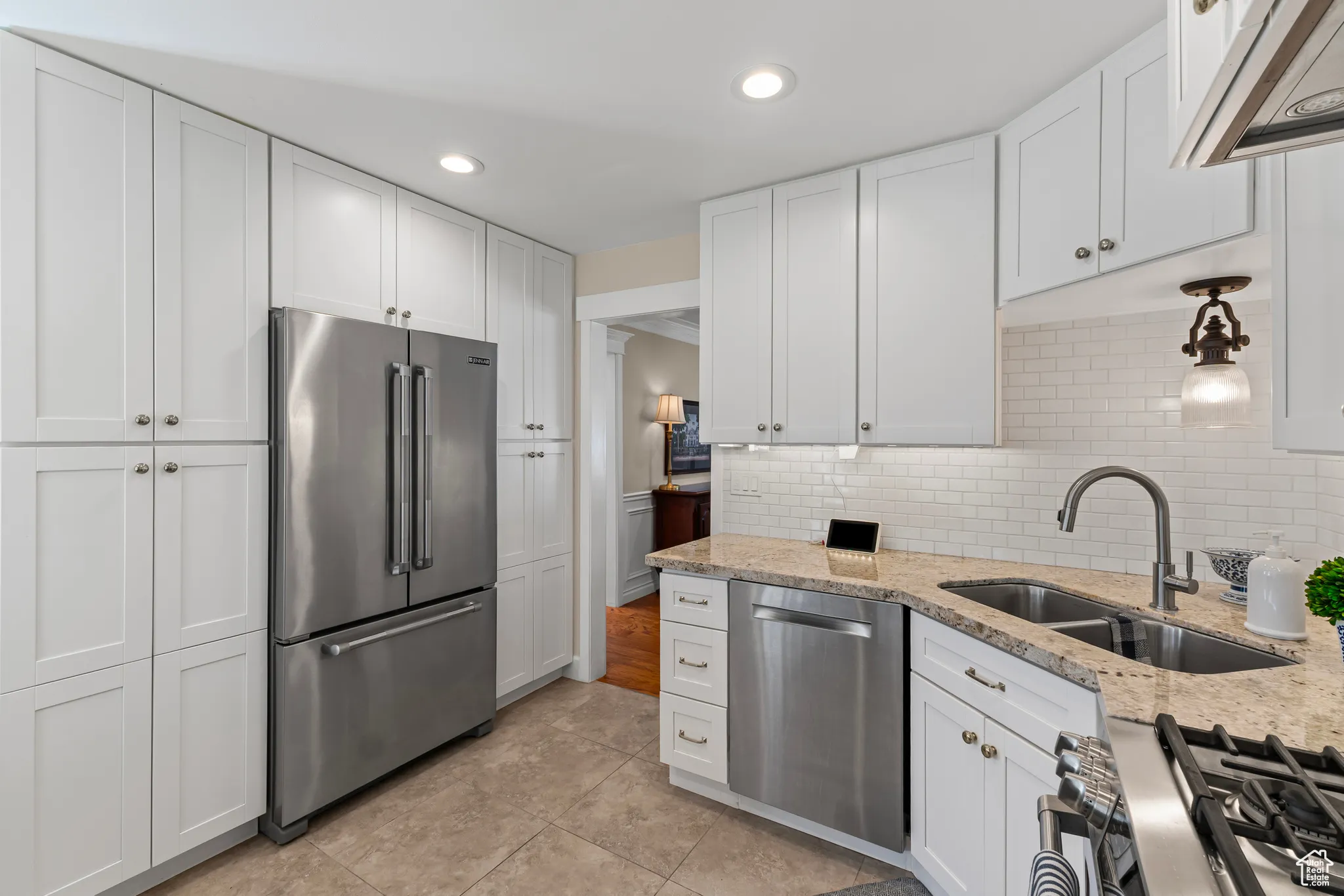 Kitchen with stainless steel appliances, white cabinetry, recessed lighting, light stone countertops, and extractor fan