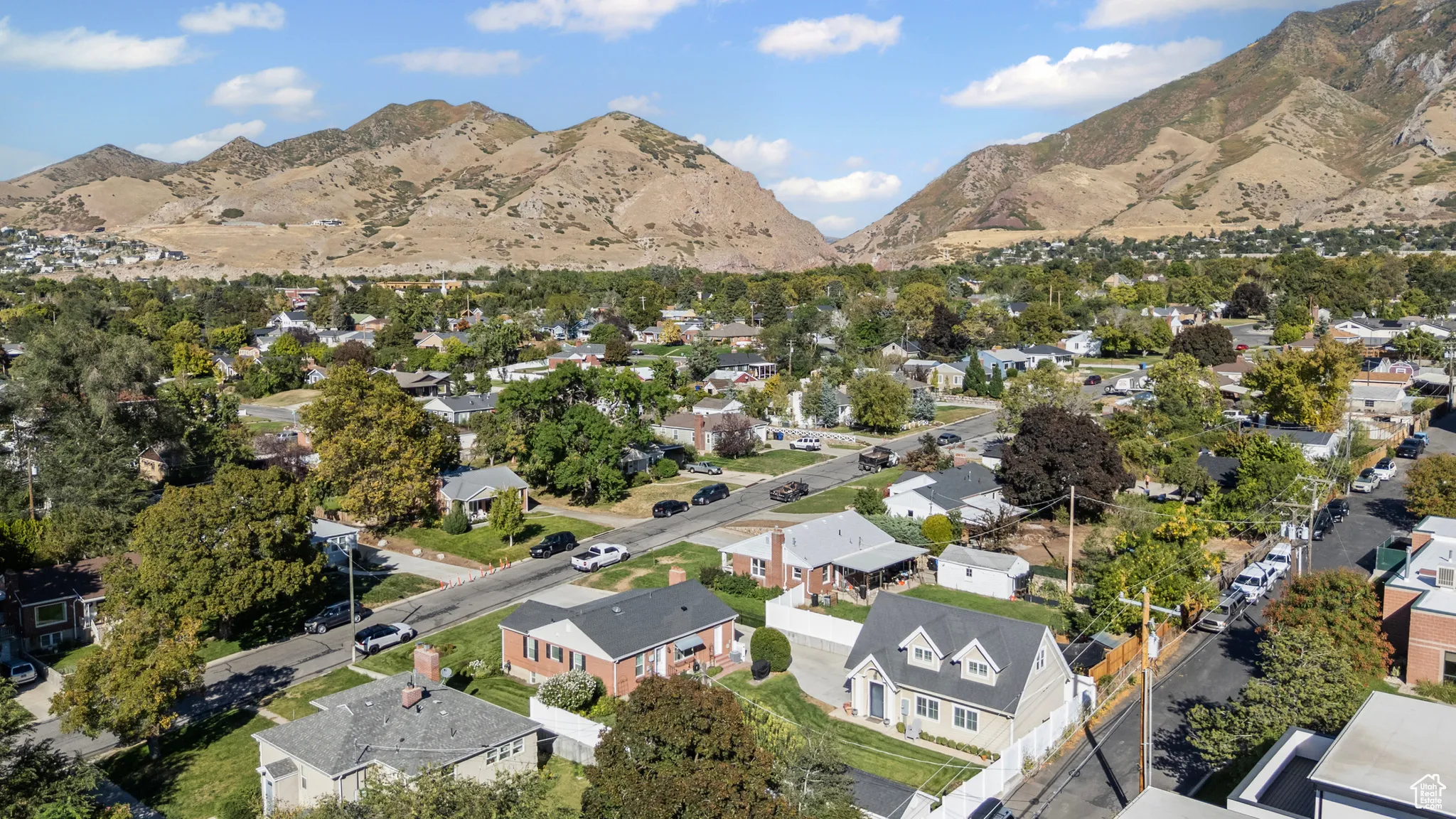 Aerial view of property and surrounding area featuring nearby suburban area and a mountainous background