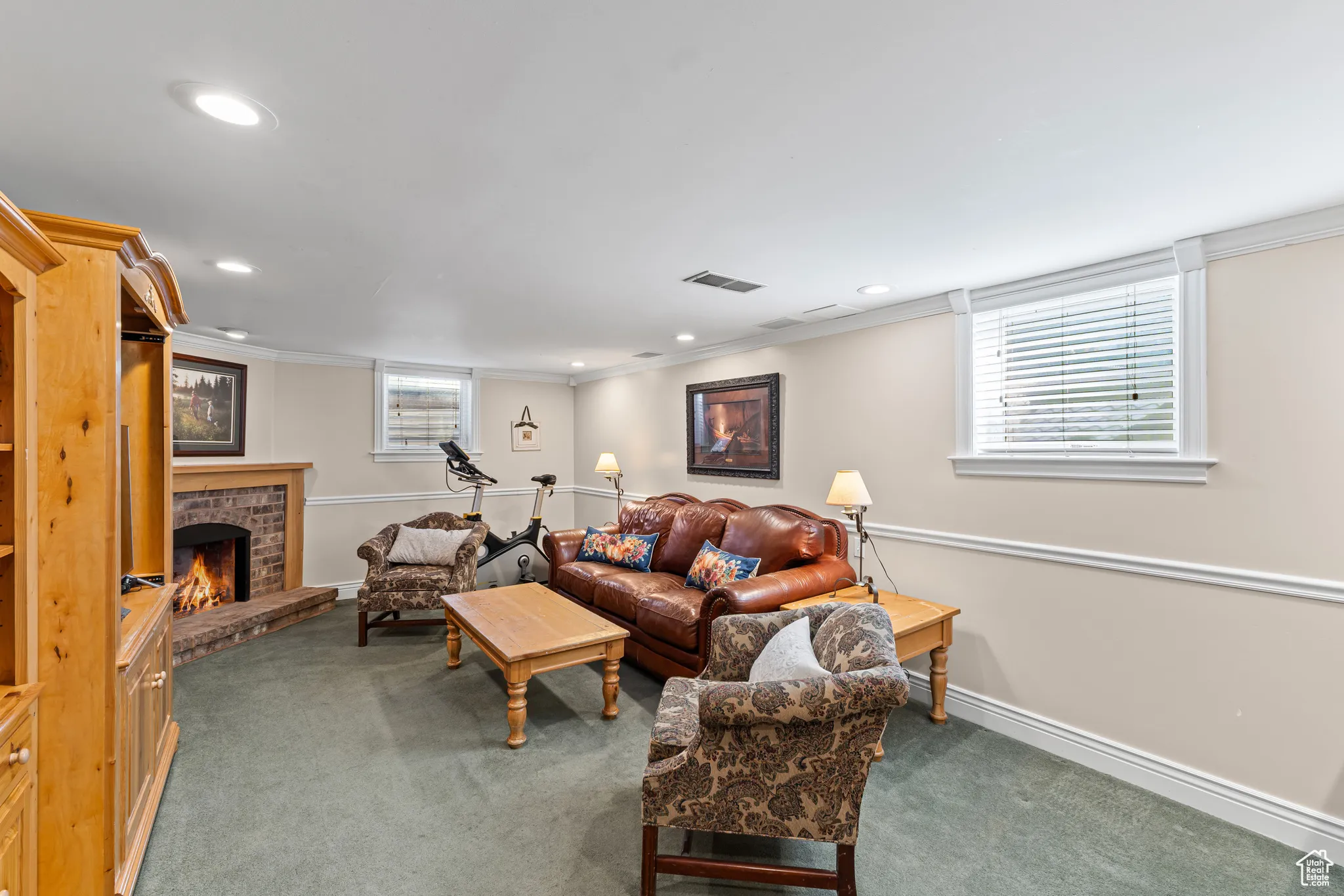 Living room with dark colored carpet, a fireplace, ornamental molding, and recessed lighting