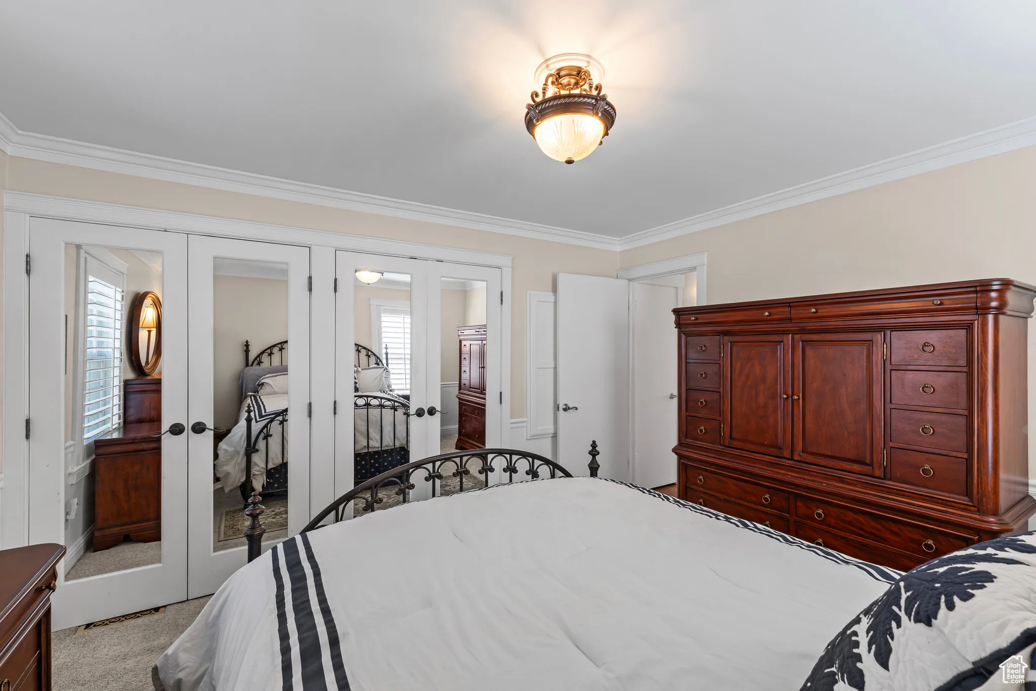 Carpeted bedroom featuring french doors, ornamental molding, and a closet