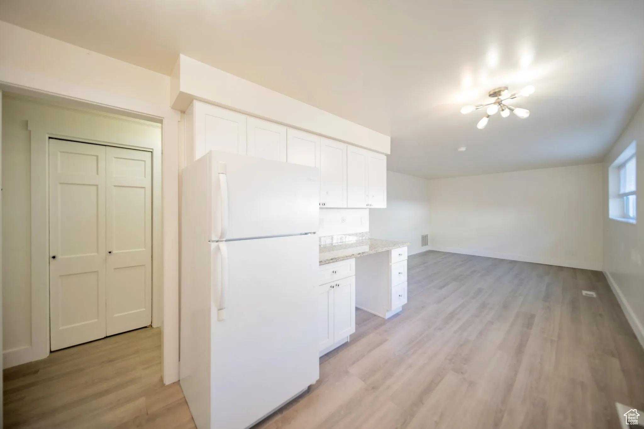 Kitchen featuring freestanding refrigerator, white cabinets, and light wood finished floors