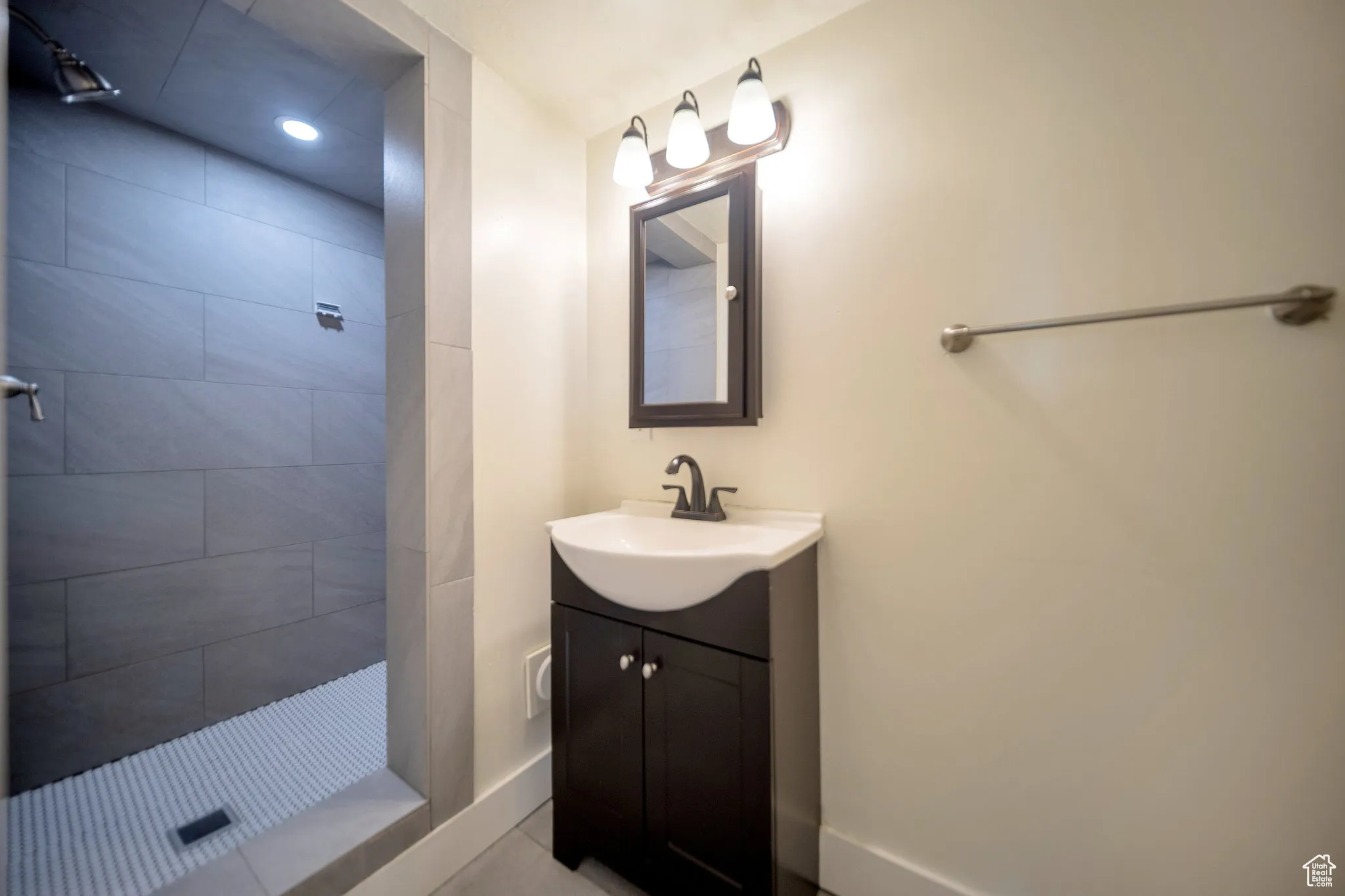 Full bathroom featuring a stall shower, vanity, and light tile patterned floors