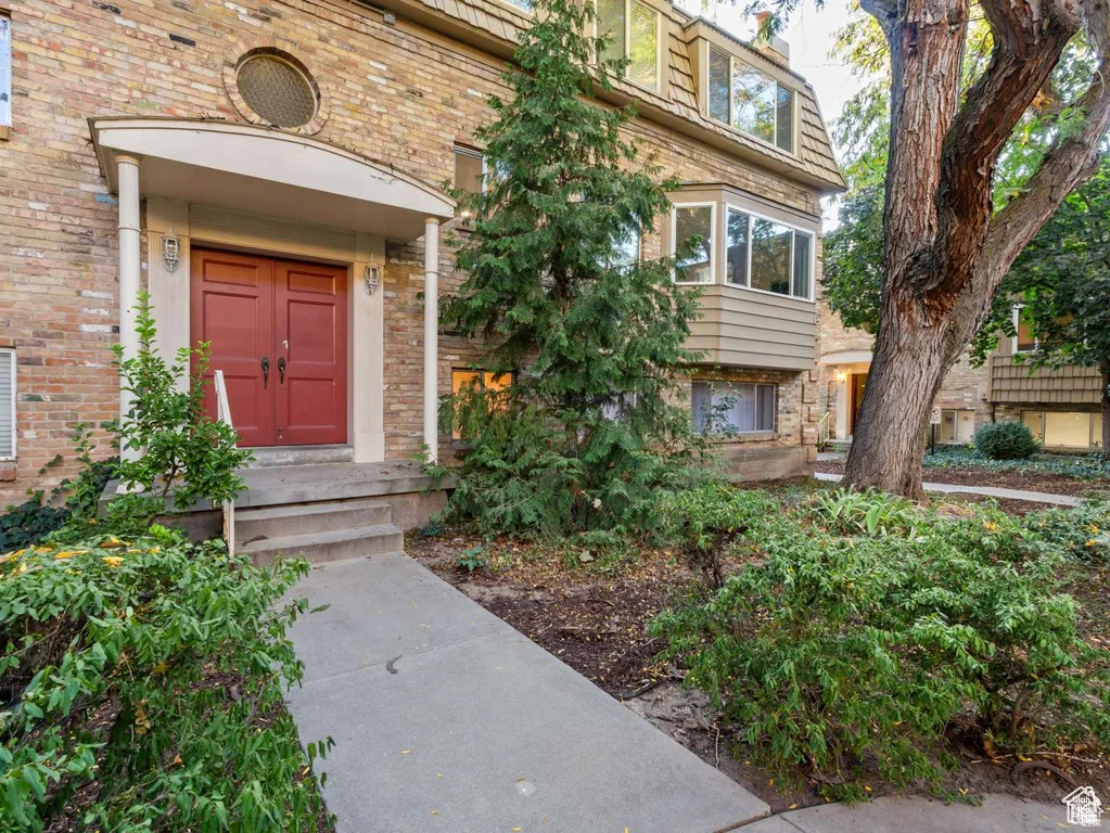 Entrance to property featuring mansard roof and brick siding