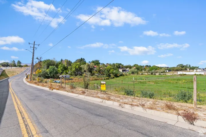 View of asphalt street with street lights, curbs, and a view of rural / pastoral area