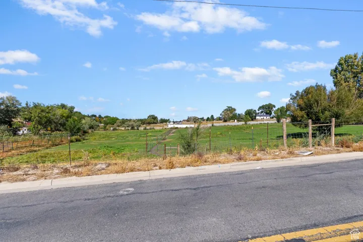 View of asphalt road featuring a rural view and curbs