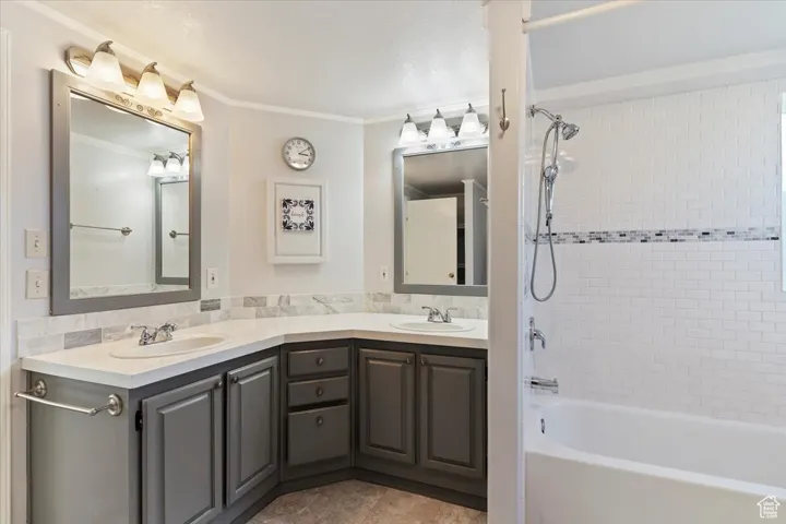 Bathroom with  shower combination, double vanity, light tile patterned floors, and ornamental molding