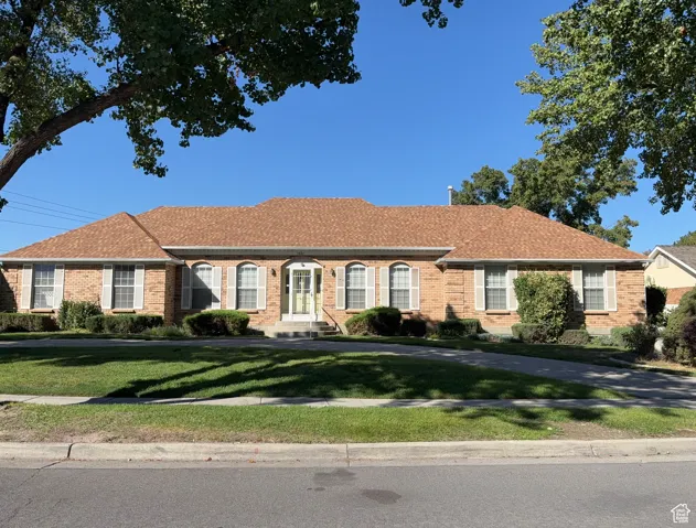 Single story home featuring brick siding, a front lawn, and a shingled roof