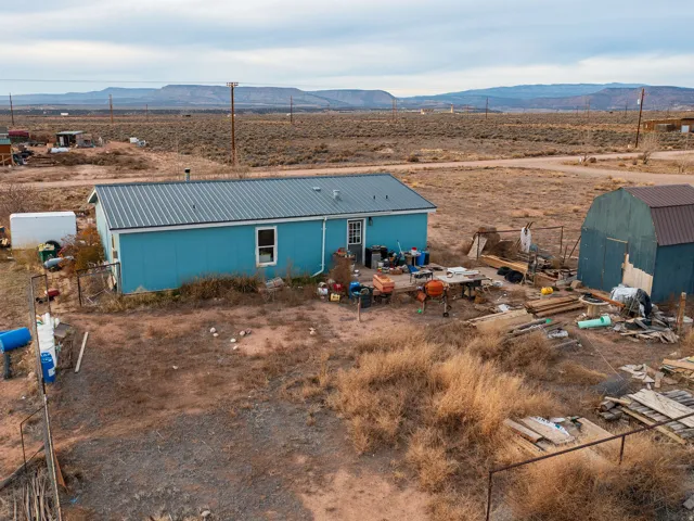 Rear view of property featuring a mountain view, a metal roof, an outbuilding, and a view of countryside