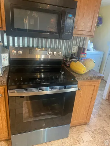 Kitchen view of black microwave, stainless steel range with electric cooktop, and brown cabinetry