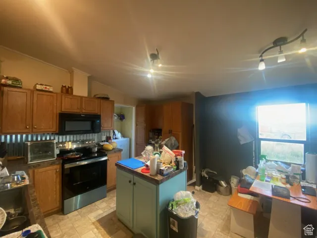 Kitchen featuring stainless steel electric range oven, black microwave, a center island, brown cabinetry, and vaulted ceiling