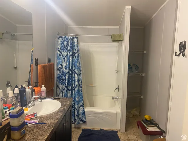 Bathroom with shower / bathtub combination with curtain, vanity, light tile patterned floors, and ornamental molding
