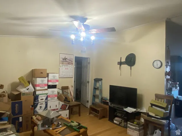Living room with light wood-style floors, ornamental molding, and a ceiling fan