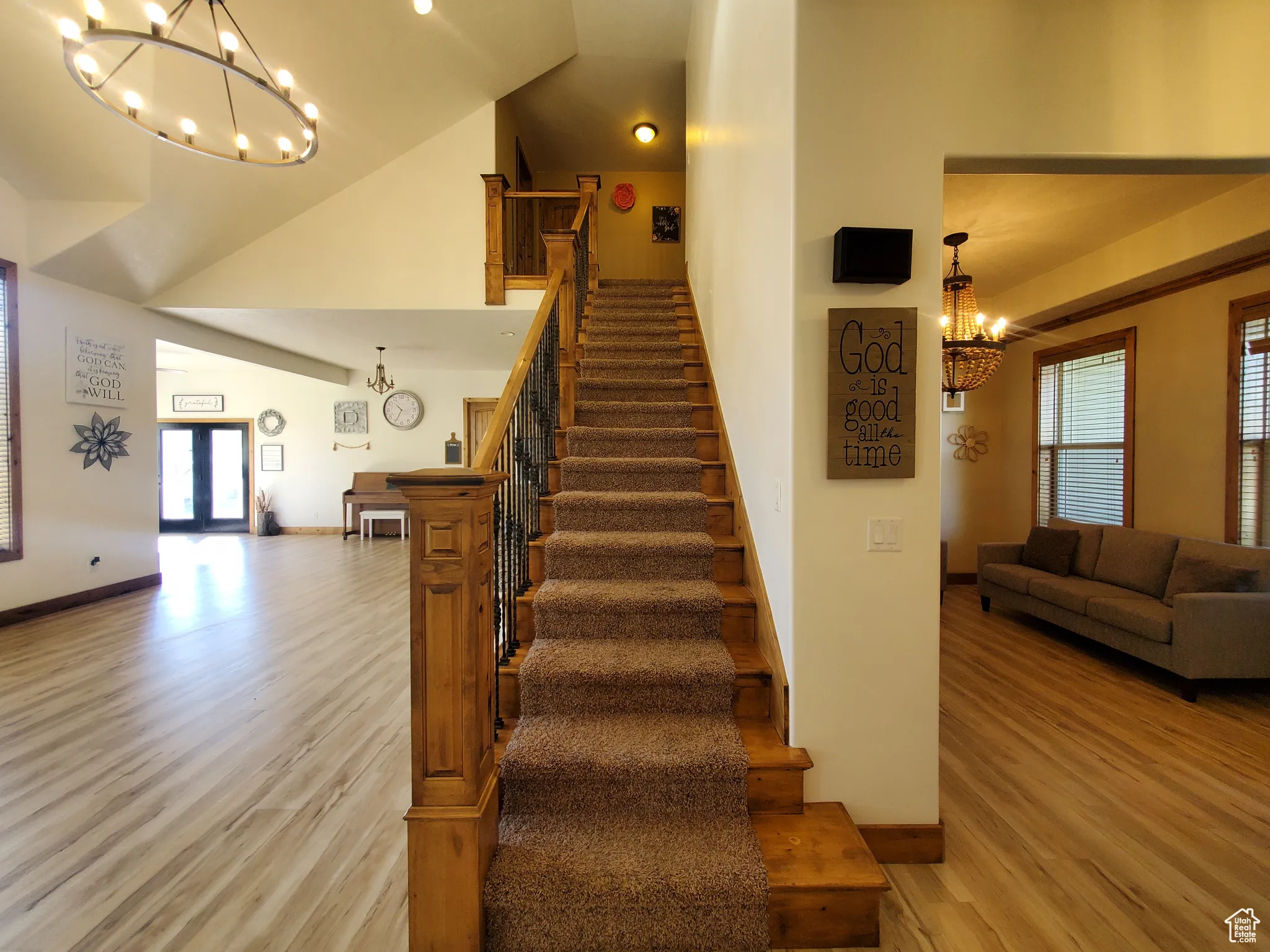 Stairs going to second level with a chandelier, wood finished floors, and high vaulted ceiling