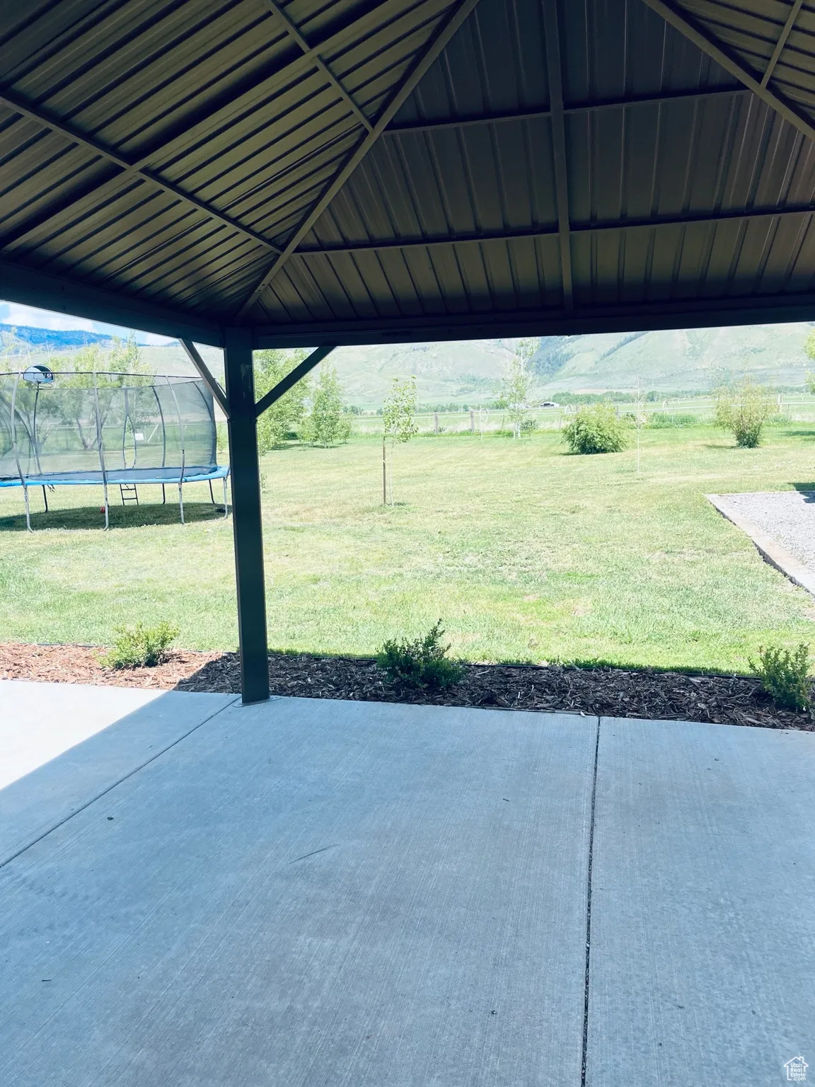 View of patio with a trampoline and a rural view of back yard, beautiful  mountain setting