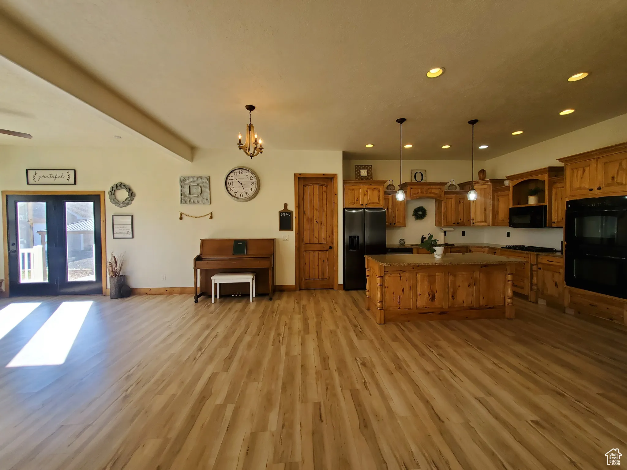 Kitchen featuring open floor plan, black appliances, recessed lighting, hanging light fixtures, and a kitchen island