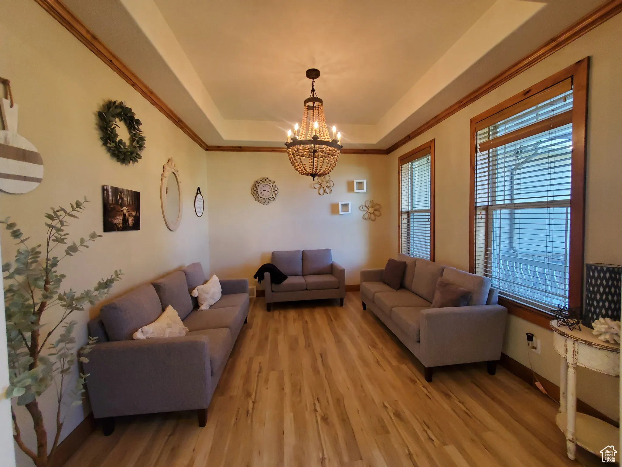 Formal Living room featuring a raised ceiling, a chandelier, light wood-style floors, and ornamental molding