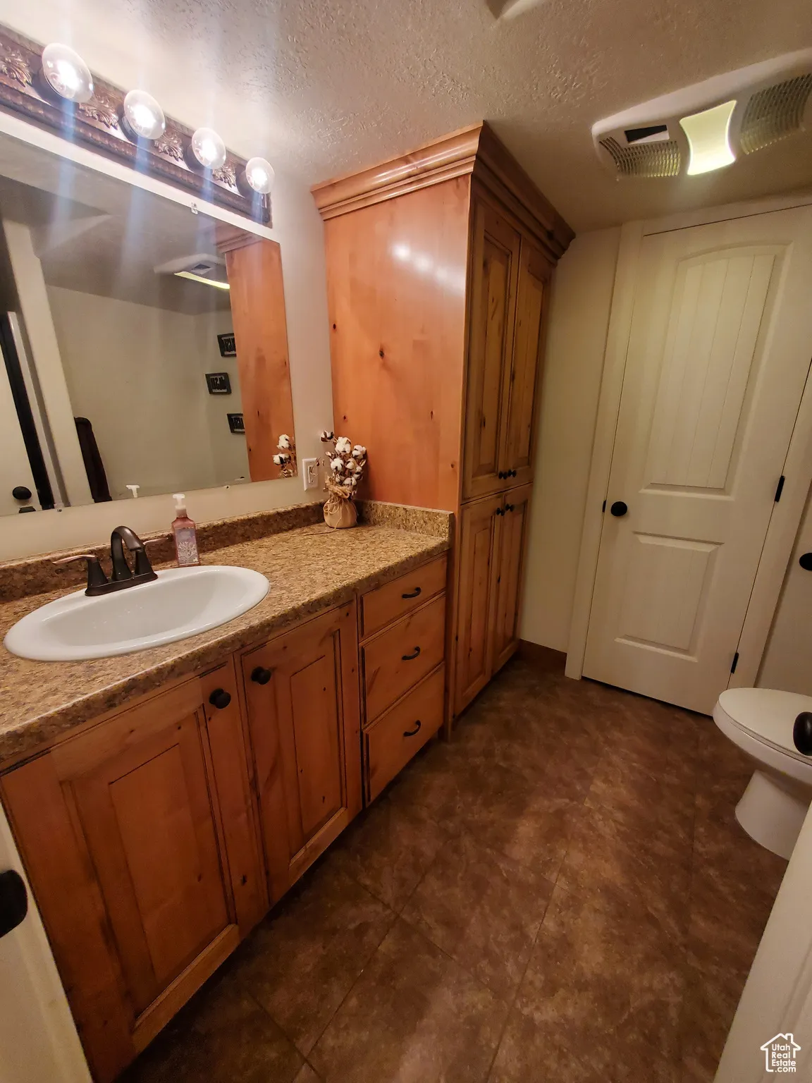 Full Bathroom in basement featuring vanity and a textured ceiling
