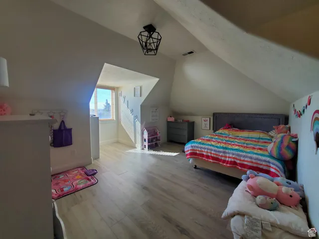 Bedroom #2upstairs with wood finished floors and vaulted ceiling