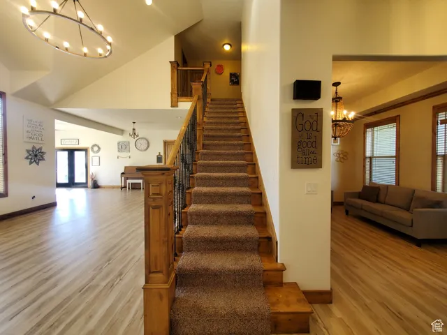 Stairs going to second level with a chandelier, wood finished floors, and high vaulted ceiling