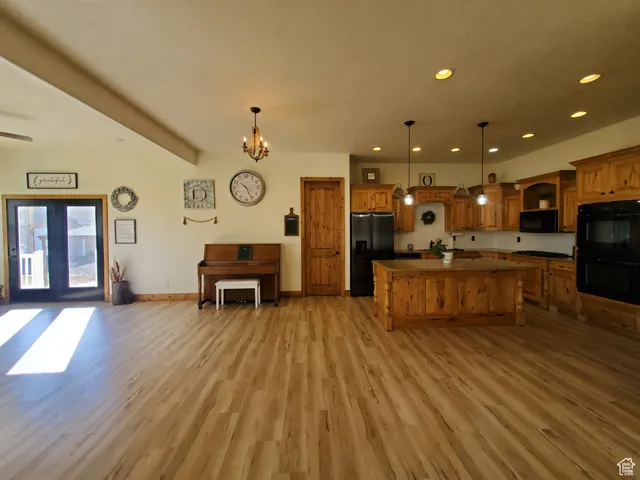 Kitchen featuring open floor plan, black appliances, recessed lighting, hanging light fixtures, and a kitchen island
