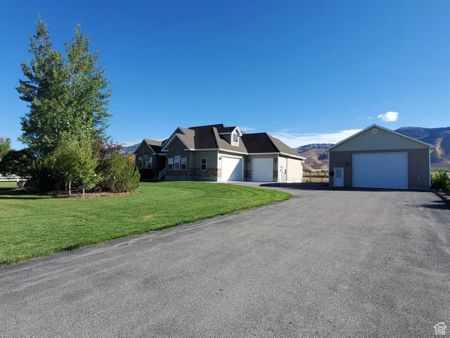 View of front of house with a mountain view, stone siding, a front yard, and a garage