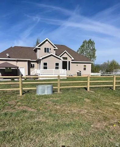 Exterior features include a two-story home with light-toned siding, a brown shingle roof, and a white deck with railings