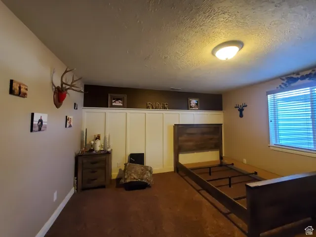 Bedroom #2 in basement with adorable board and batten accent wall, a textured ceiling and carpet floors