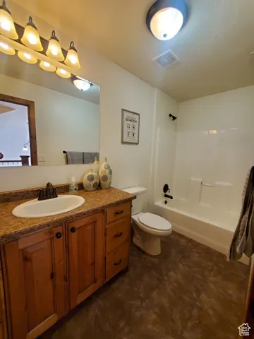 Bathroom upstairs with bathing tub / shower combination, vanity, and dark tile patterned floors