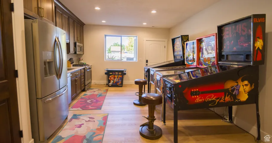 Kitchen with appliances with stainless steel finishes, light wood-style flooring, light countertops, recessed lighting, and dark brown cabinetry